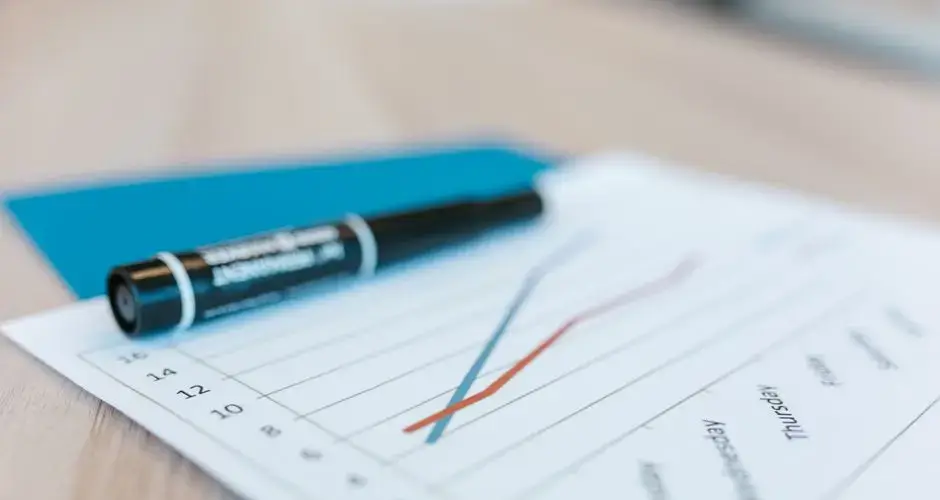 Dynamic line chart on paper with black marker on a desk, illustrating data trends.