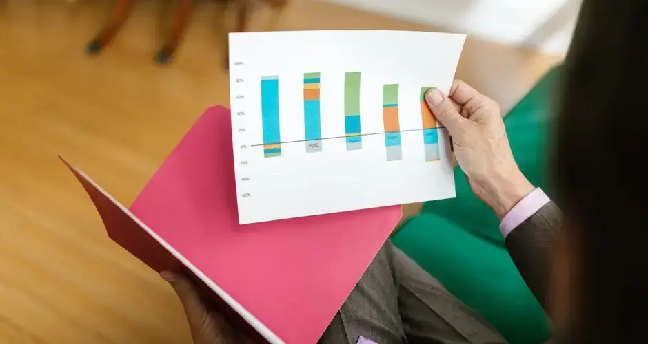 Close-up of a person analyzing a printed business report featuring a colorful bar graph.