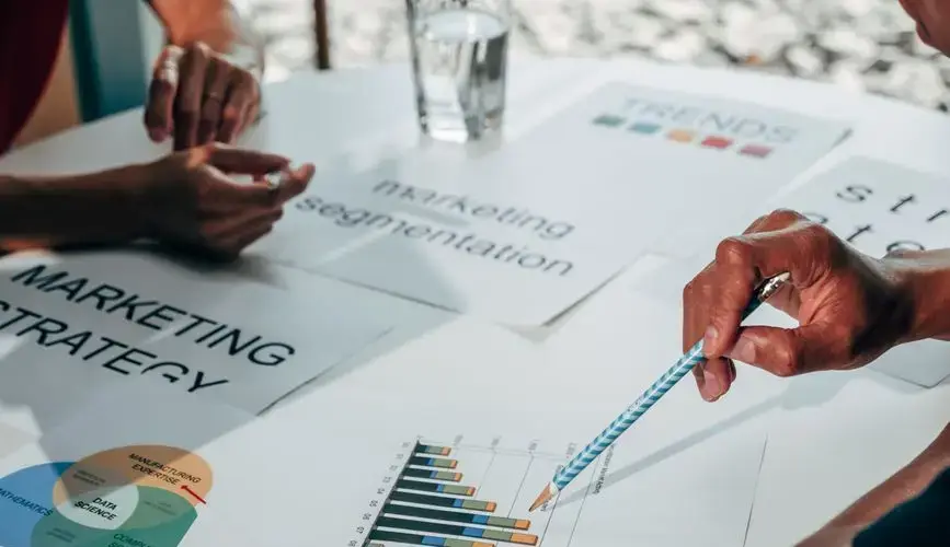 Team working on marketing strategy using data charts and papers in an office meeting.