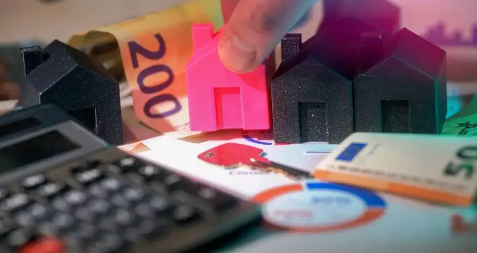 Miniature houses, Euro bills, and calculator representing real estate investment.