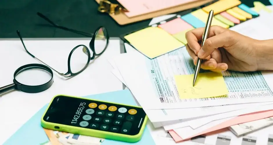 Close-up of an office desk with a calculator, glasses, and documents for financial planning.