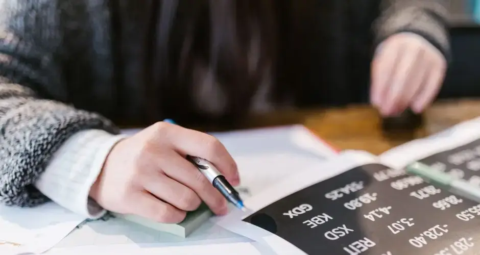 Close-up of a woman reviewing financial documents with focus on numbers and calculations.