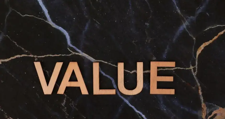 A close-up of wooden 'Value' letters placed on a dark marble background, emphasizing texture and concept.