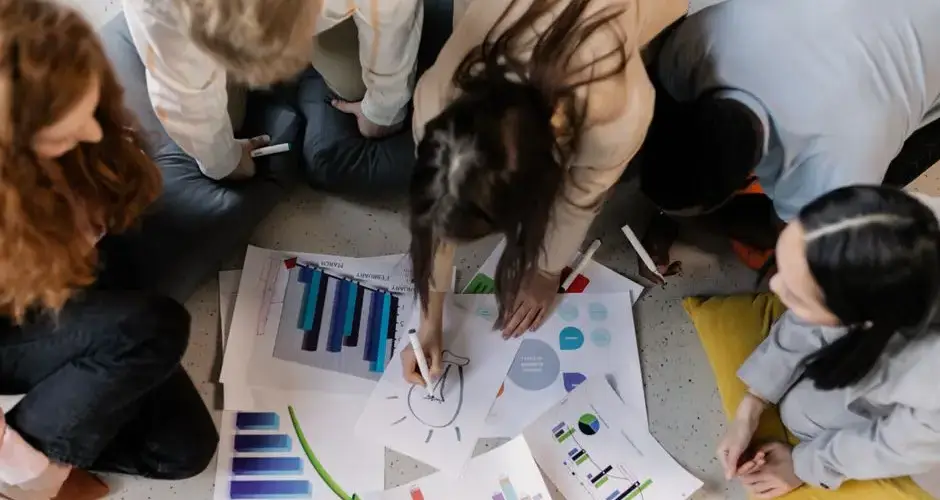 Overhead view of diverse team brainstorming on business strategy using charts and graphs.