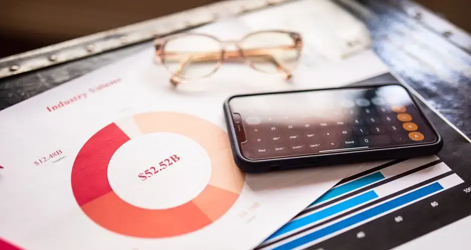 Smartphone on business documents with charts and graphs, illustrating financial analysis.