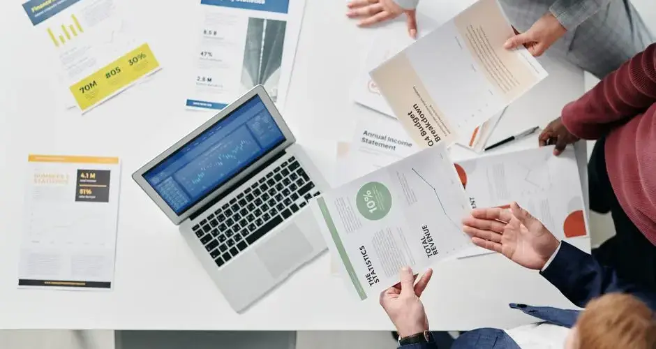 Top view of a professional office meeting with documents and laptop on the table.