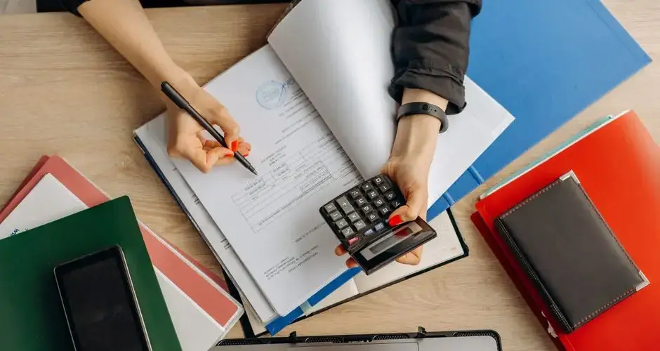 Accountant analyzing financial documents with a calculator on a desk, highlighting business tasks.