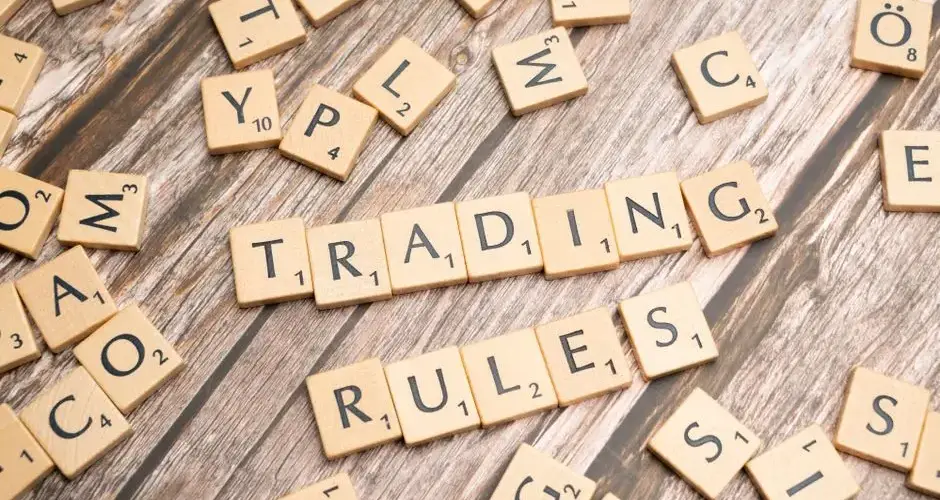 Wooden letter tiles arranged to spell 'Trading Rules' on a wooden surface.
