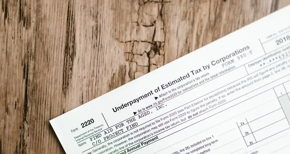 Close-up of a corporate tax form on a textured wooden surface, highlighting document details.