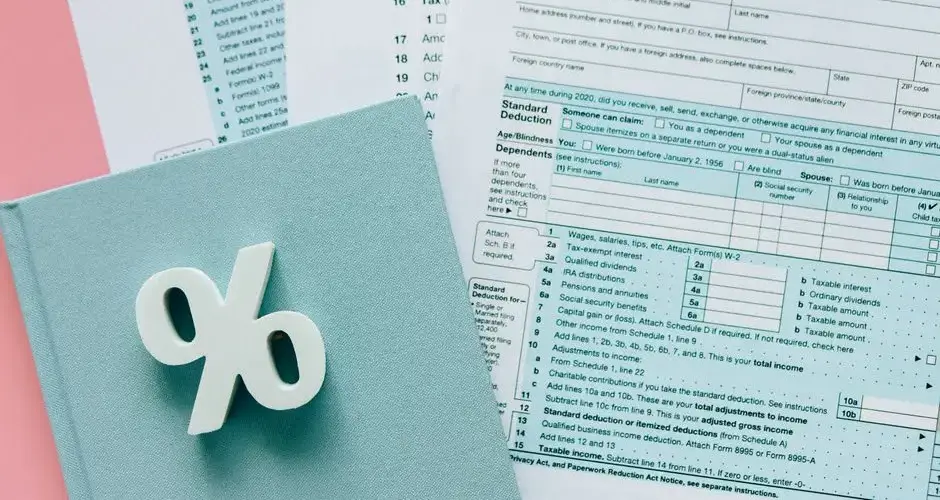 Tax documents with a percentage symbol on a pink and blue desk setup, emphasizing finance.
