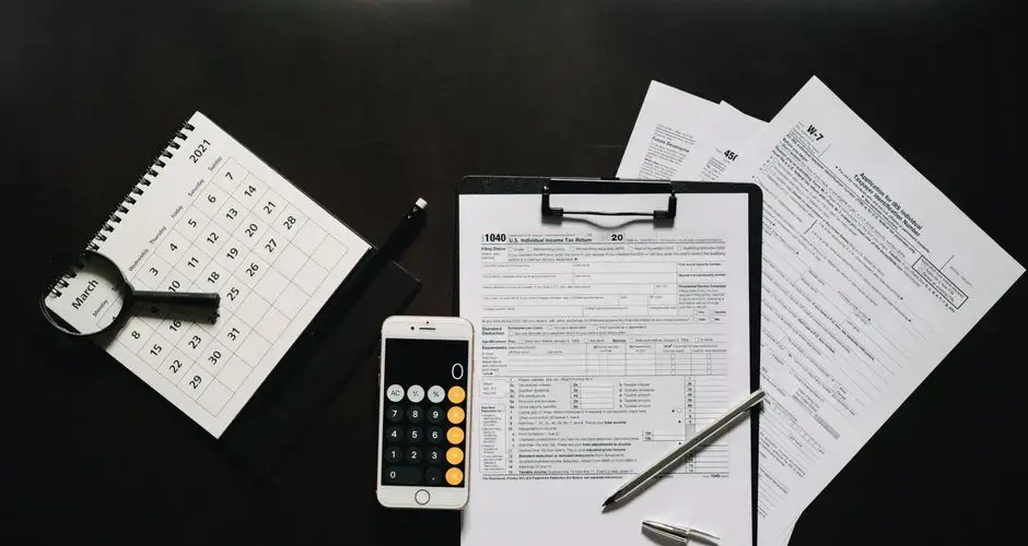 Flat lay of financial tools for tax preparation including forms, calculator, and calendar.