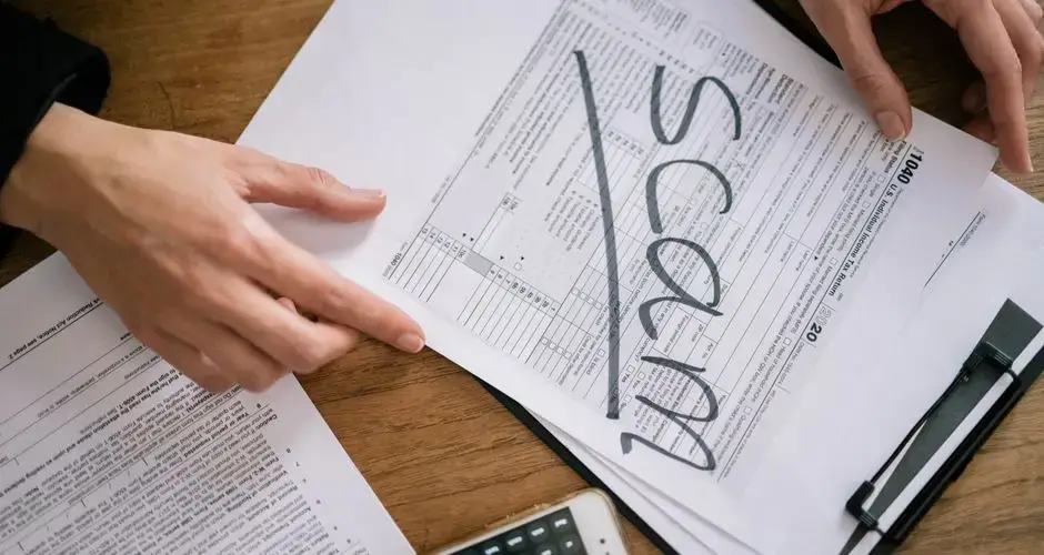 Documents highlighting tax fraud with the word 'scam' on tax forms.