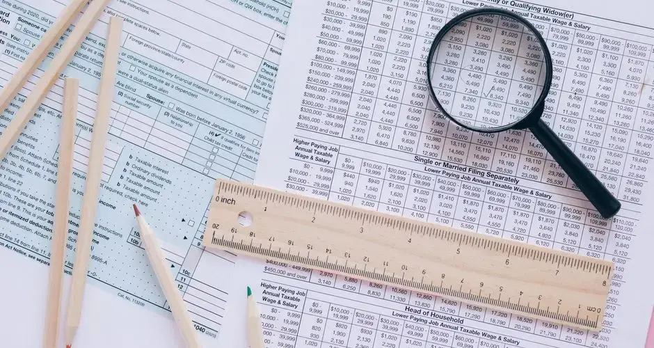 A high angle view showing IRS tax forms with pencils, ruler, and magnifying glass for financial planning.
