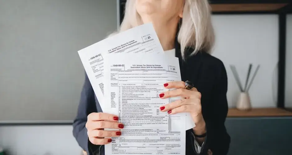 Businesswoman holding tax documents, ready for filing or review, in a professional office setting.