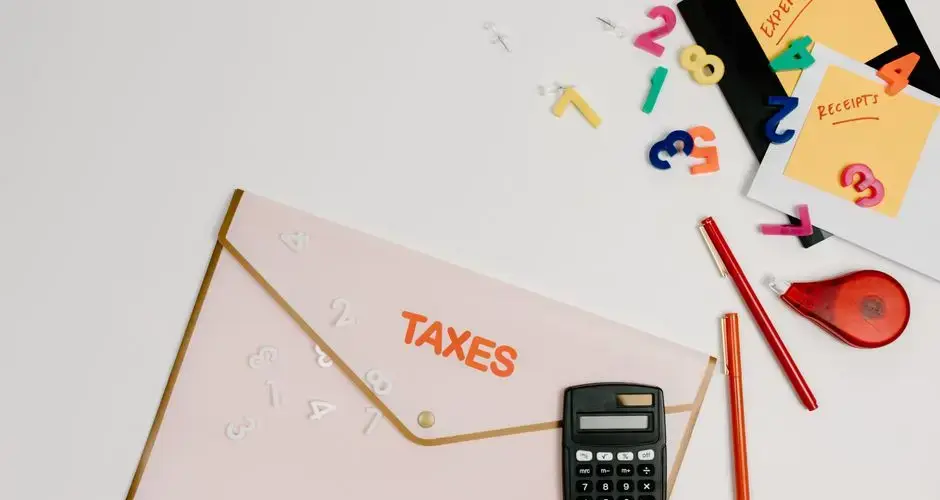 Flat lay of a tax preparation workspace with calculator, envelope, and colorful numbers.