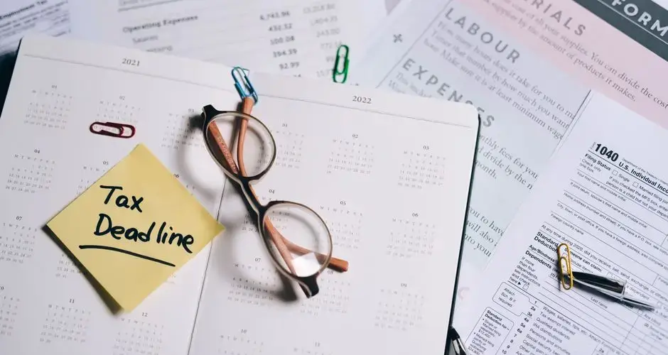 A calendar marked with "Tax Deadline" surrounded by financial documents and eyeglasses.