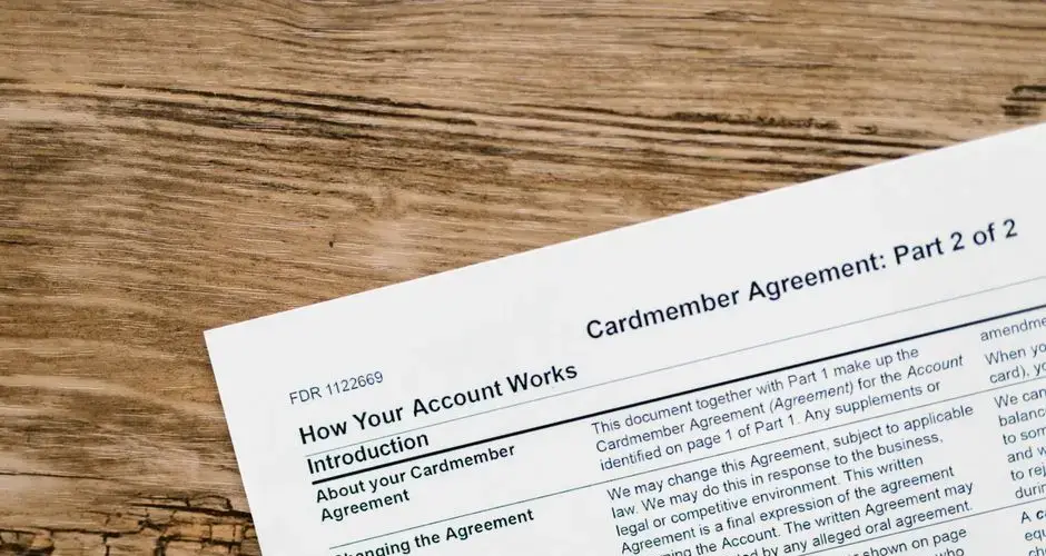 Close-up of a credit card agreement document on a textured wooden desk.