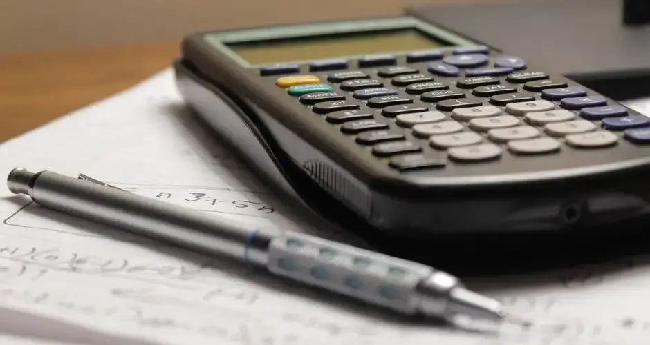 A detailed view of a calculator and pen resting on mathematical notes, ideal for educational and financial themes.