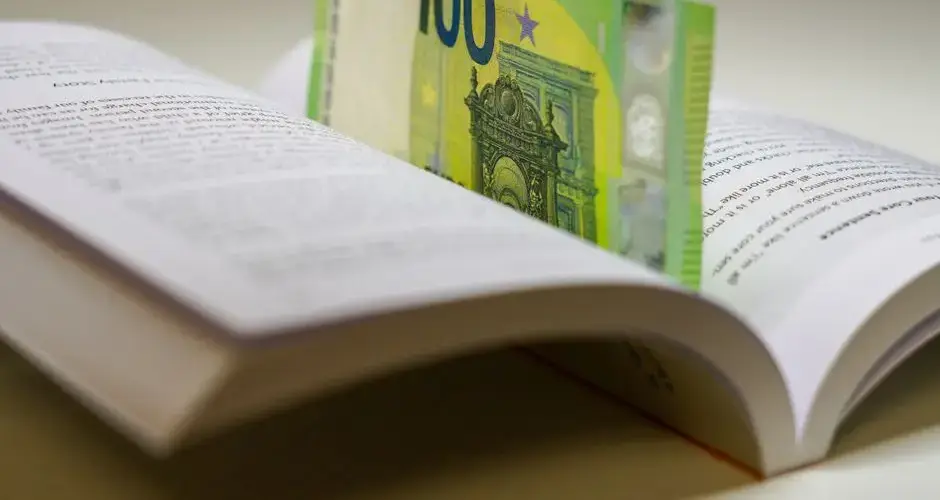 A 100 euro bill used as a bookmark between open pages of a book, symbolizing wealth and knowledge.