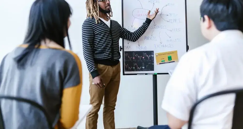 Diverse team discusses cryptocurrency strategies using a whiteboard during a meeting.