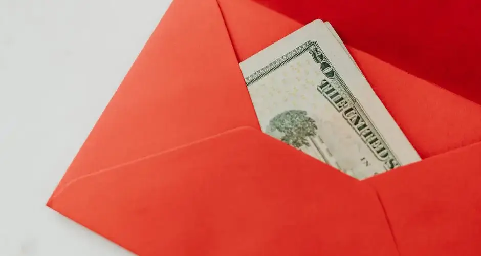 A red envelope containing U.S. dollar bills, symbolizing wealth and gifting.