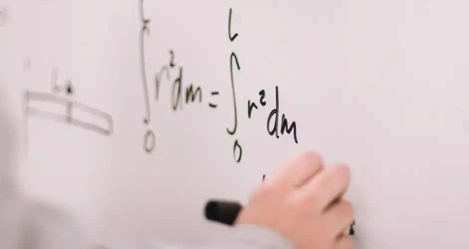 Person writing math equations on a whiteboard, focusing on integrals and formulas.