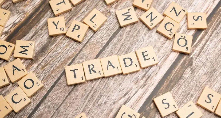 Scrabble letter tiles spelling 'trade' on a wooden surface, illustrating business concepts.