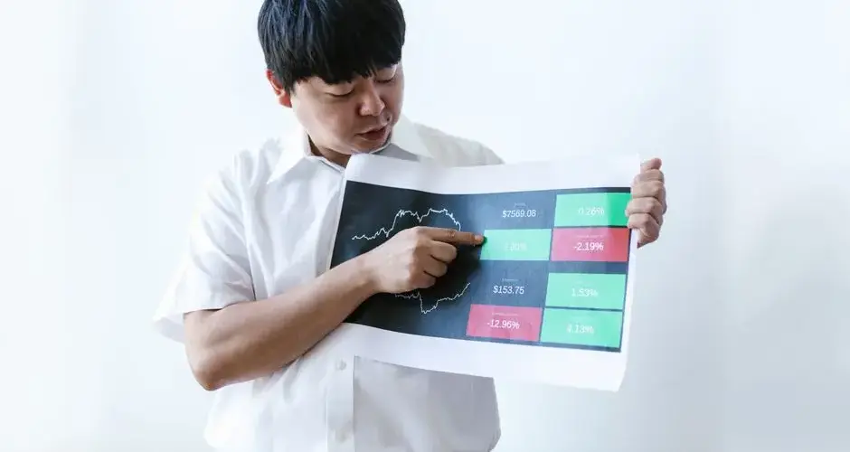 Asian businessman in white shirt presenting cryptocurrency market data on chart.