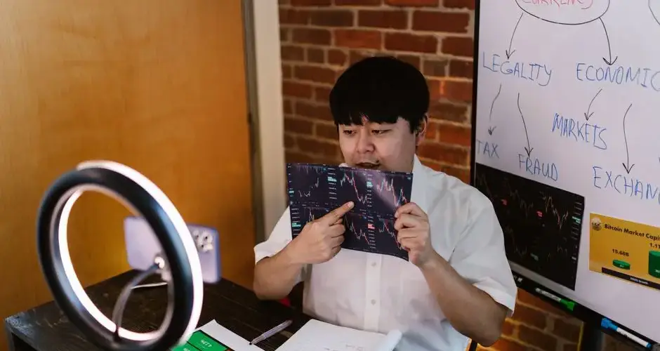 Man analyzing cryptocurrency data with ring light and flip charts in a home office.