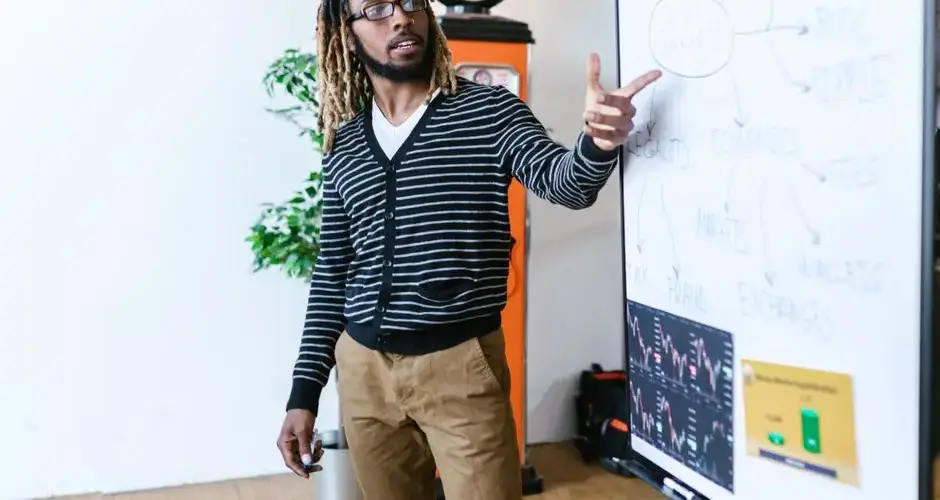 Man explaining cryptocurrency concepts on a whiteboard in a modern office setting.