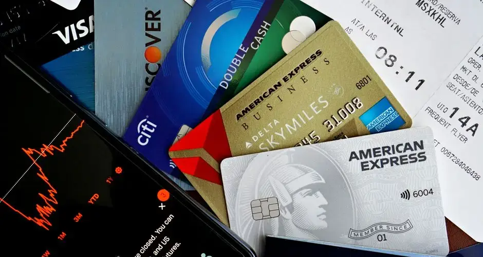 Flat lay of credit cards, passport, and a phone showing stock data, depicting finance and travel.