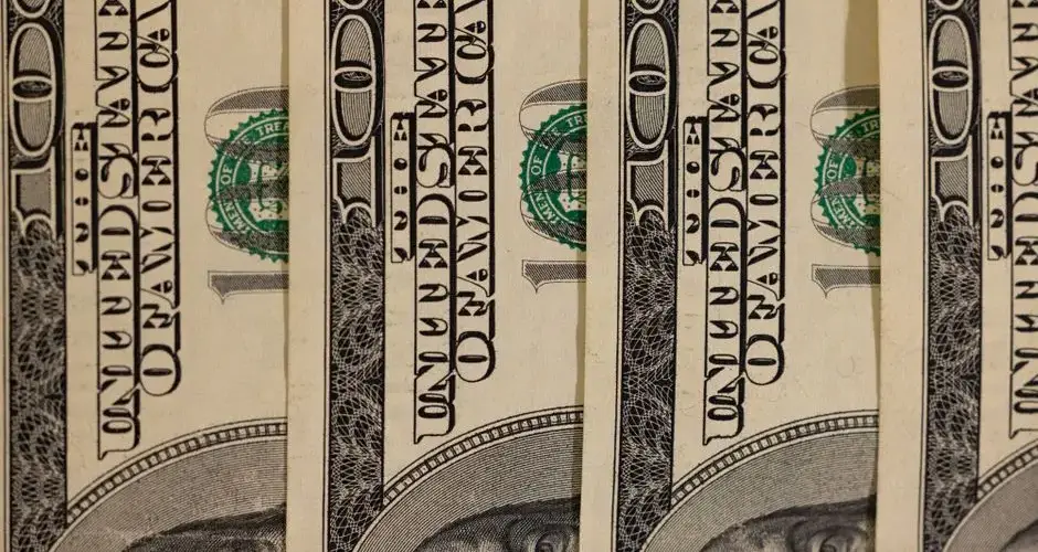 Detailed close-up of multiple US hundred dollar bills, showcasing currency design.