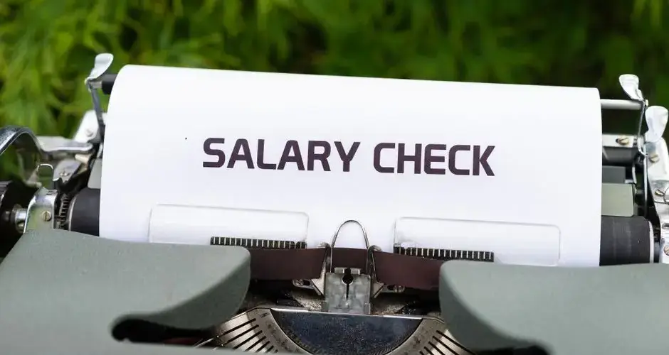 Close-up of a vintage typewriter typing 'Salary Check' on paper, symbolizing payroll and finance.