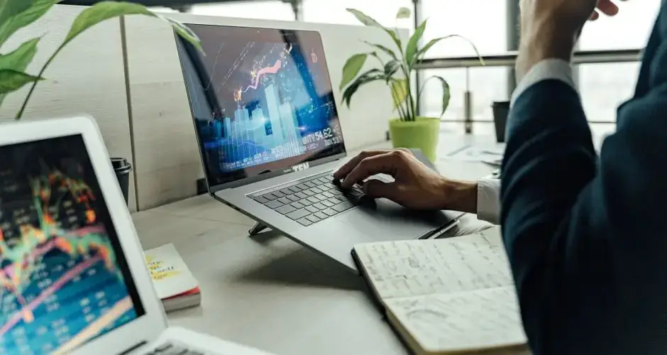 A professional analyzing stock market data on a laptop in a bright office environment.