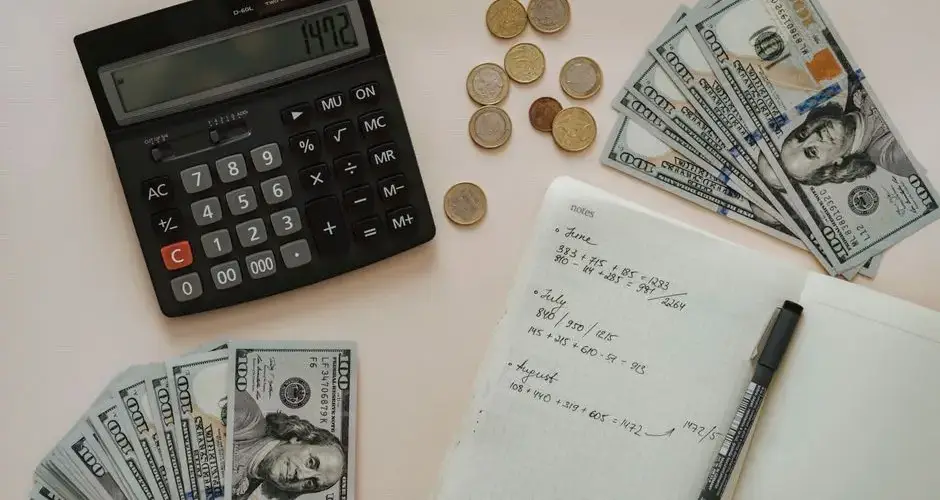 Flat lay of calculator, cash, coins, and handwritten notes for budget planning.