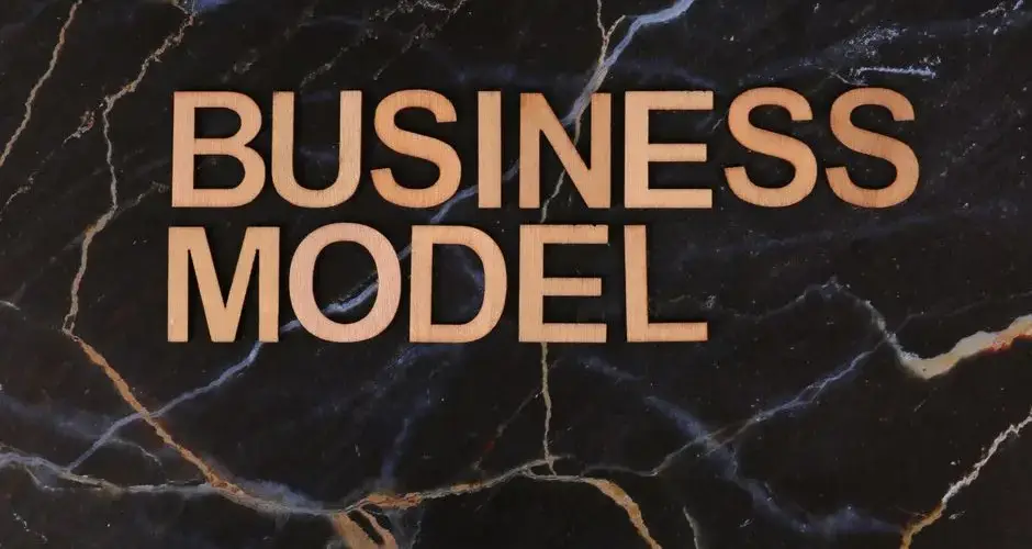 Wooden letters spelling 'BUSINESS MODEL' on a dark marble background.