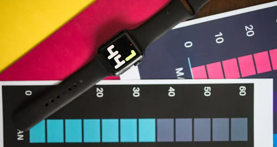 A smart watch resting on vibrant charts showing data visualization on a table.