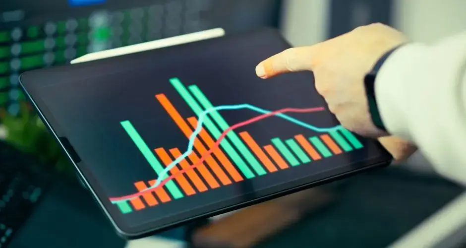 A person analyzing business data with colorful graphs on a tablet screen.