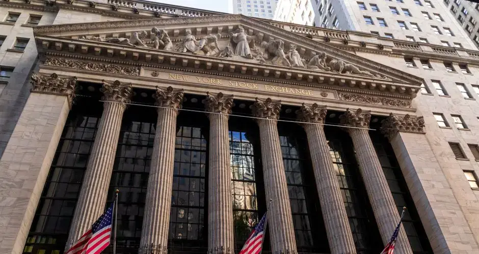 Iconic neoclassical facade of the New York Stock Exchange with American flags.
