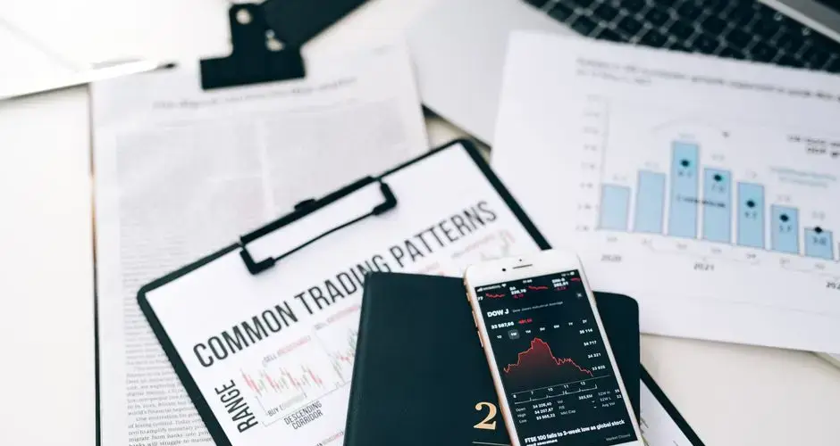 Overhead view of financial graphs and smartphone displaying stock market trends on a desk.