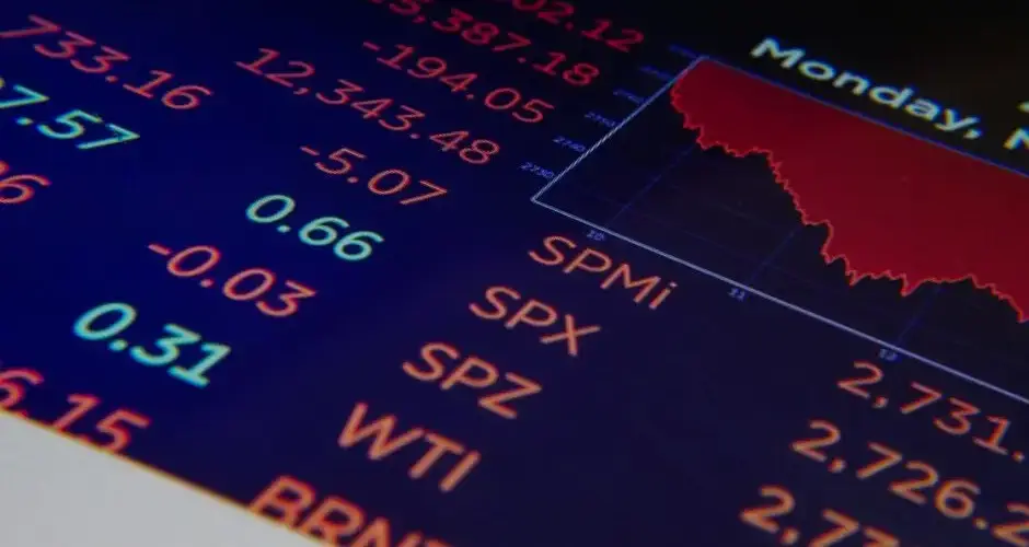 Close-up of a digital stock market graph showing falling trends and financial indices in red and green.