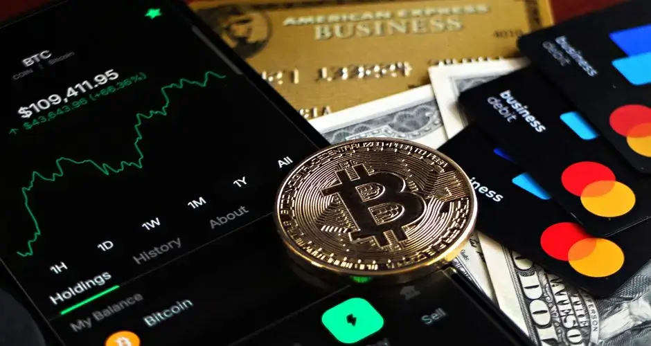Bitcoin coin with financial data, credit cards, and currency on a desk.