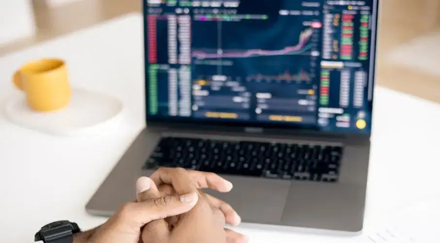 Close-up of a person analyzing stock data on a laptop with graphs and charts visible.