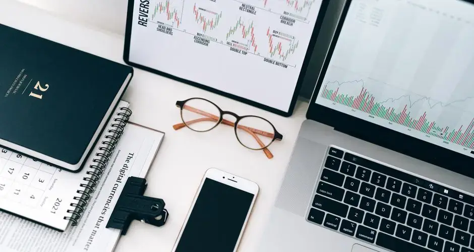 Organized workspace featuring laptop, smartphone, and graphs displaying financial data.