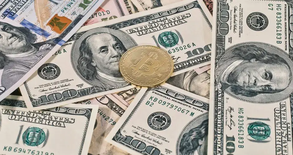 Bitcoin coin placed on scattered US dollar bills, representing cryptocurrency and finance.