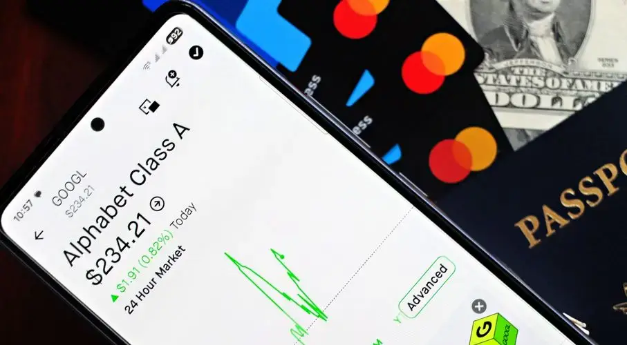 Smartphone displaying stock market app next to U.S. dollar and passport, representing global finance.