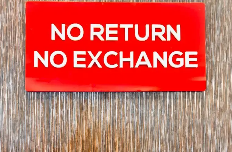 Bold red sign with 'No Return No Exchange' message on a wooden backdrop.