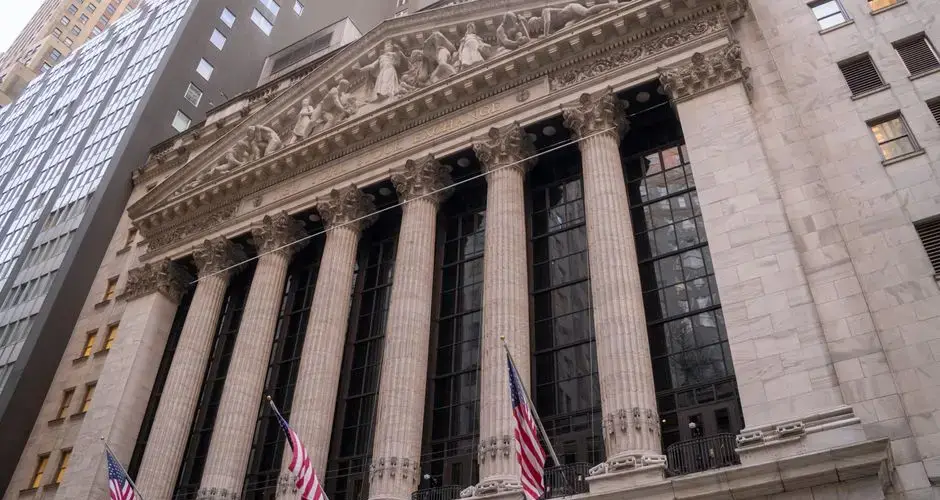 Close-up view of the iconic New York Stock Exchange building with American flags, located in Wall Street, NYC.