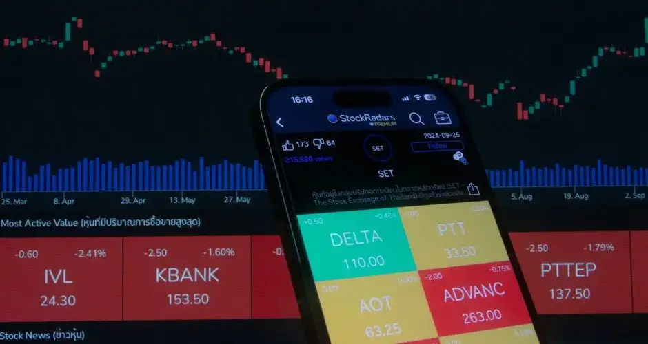 Mobile screen displaying stock trading app with market graphs in background.