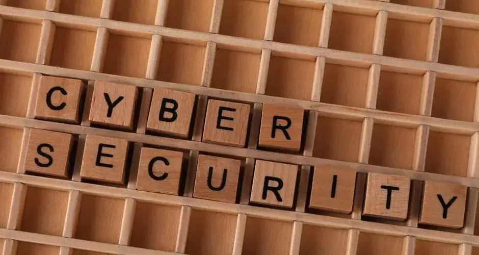 Wooden letter blocks spelling 'CYBER SECURITY' on a wooden grid background for data protection themes.